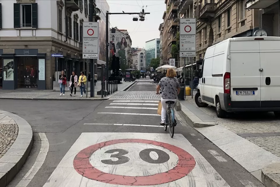 A bike rider navigates a bike lane in a traffic limited zone in Italy, where only one delivery van is visible on the street.